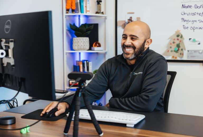 Insurance professional at Insurit Agency smiling while working at his desk, helping real estate investors and business owners secure tailored coverage in Grand Rapids, MI.